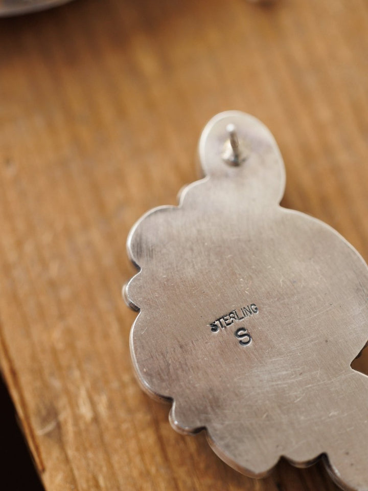 A close-up of the back of a Watseka Earring by Savannah Sevens western life{&}style, stamped STERLING S and resting on wood. The visible post highlights the quality typical of Native American handcrafted jewelry.