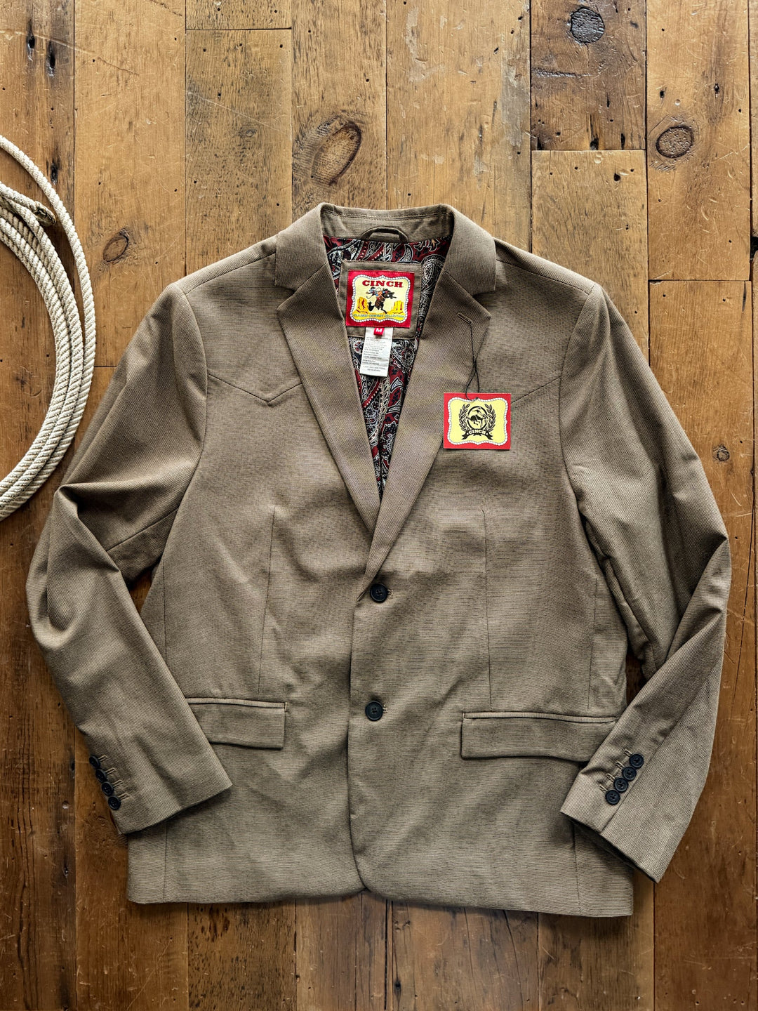 Wayne Cinch Men’s Brown Sport Coat in a micro houndstooth pattern, featuring a western stitched yoke, paisley-patterned lining, and a coil of rope on the left.