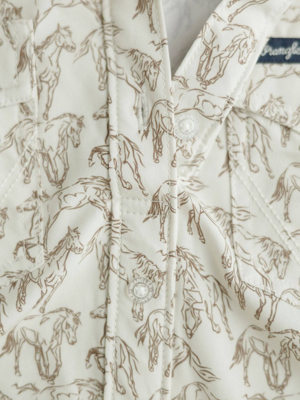 Close-up of the Weston Wrangler Horse Button Top by Savannah Sevens western life{&}style, showcasing a cream-colored print with brown line-drawn horses, visible buttons, and stitching—perfect as a women's western shirt.