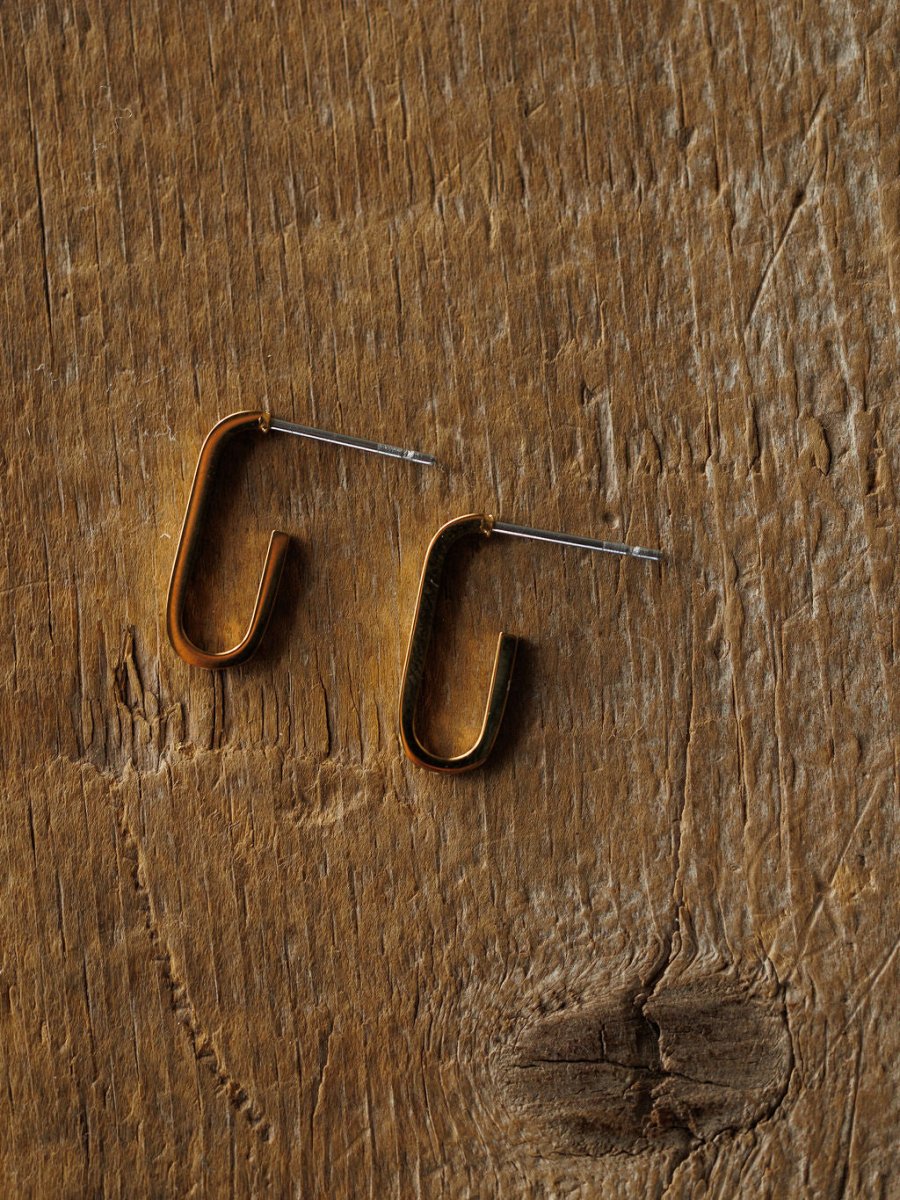The Westport Earrings by Savannah Sevens western life{&}style are minimalist 18K gold plated rectangular hoop earrings with straight posts, shown on a textured wooden surface.