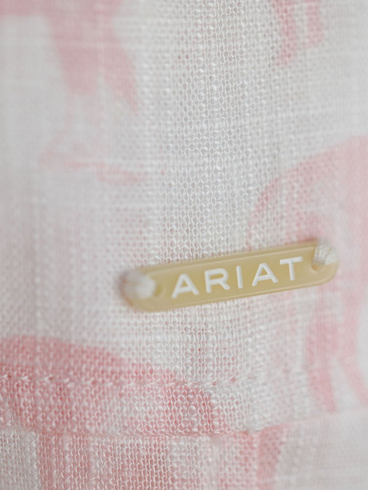 Close-up of a beige and pink woven fabric from the Westview Horse Graphic Button Up Top by Savannah Sevens western life{&}style, featuring a small rectangular beige tag with ARIAT in white capital letters.
