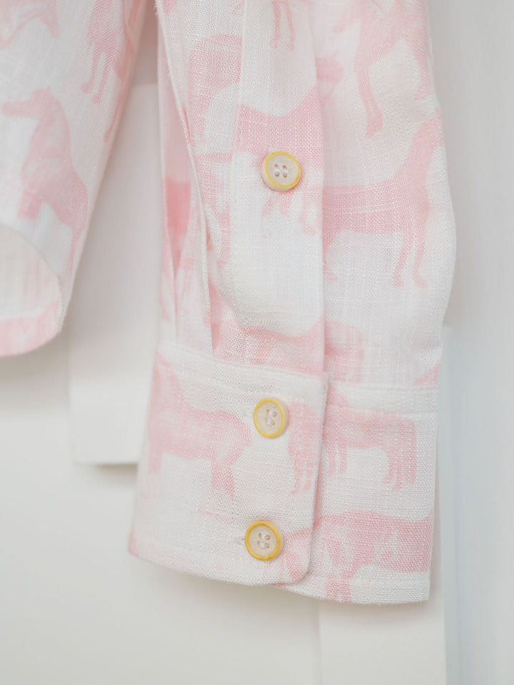Close-up of the Savannah Sevens western life{&}style Westview Horse Graphic Button Up Top with long sleeves, three light yellow buttons, and lightweight white fabric featuring a pink horse print.