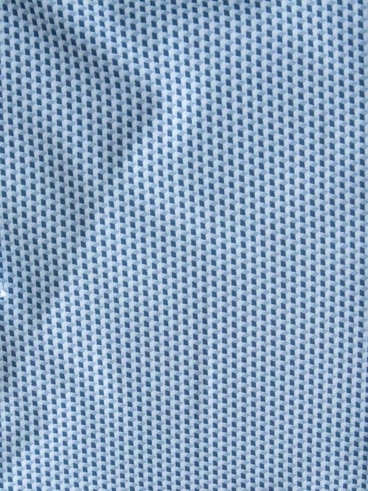 Close-up of the Willsboro Wrangler Men's Blue Button Up by Savannah Sevens western life{&}style, showcasing light blue fabric detailed with a repeating pattern of tiny dark blue squares. The geometric design and slightly wrinkled texture give this shirt its distinctive, modern look.