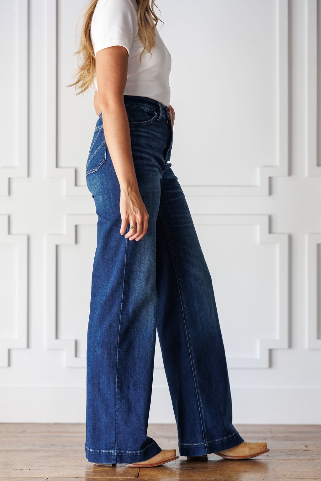 A person wears Yates High Rise Wide Leg Jean by Ariat in a medium dark wash paired with tan pointed-toe boots.
