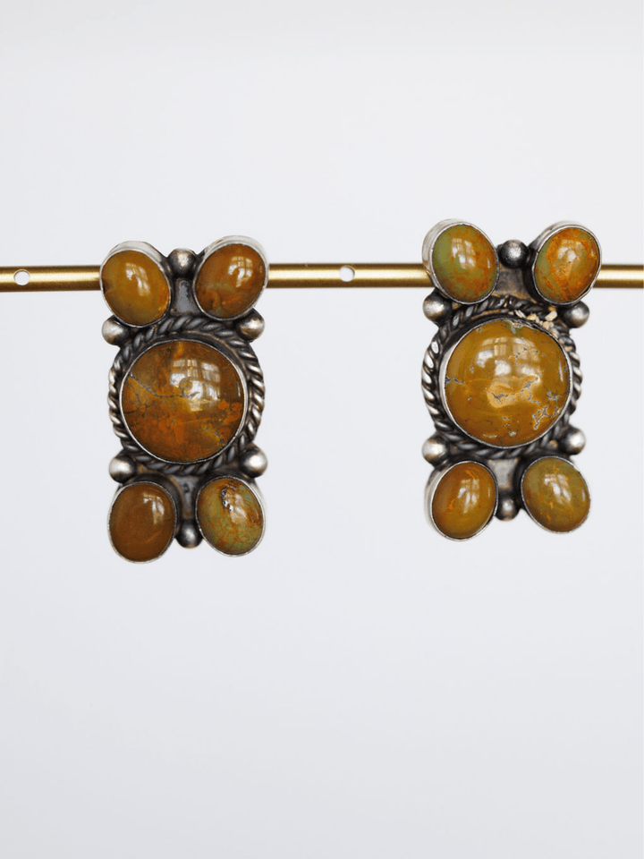 The Yuma Earrings by Savannah Sevens western life{&}style are vintage handcrafted sterling silver pieces, each with a large round orange-brown center stone and four smaller oval orange and green stones, shown on a plain white background.
