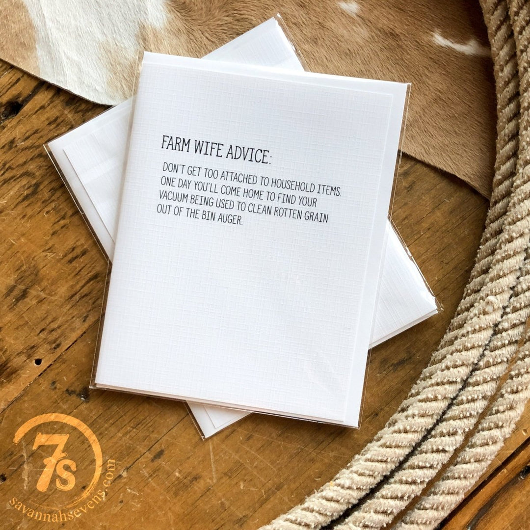 The Farm Wife Advice Card by Hungry Canyon rests on a cowhide rug with rope. Its message reads: “Don’t get too attached to household items. One day your vacuum may be cleaning rotten grain out of the auger.”.
