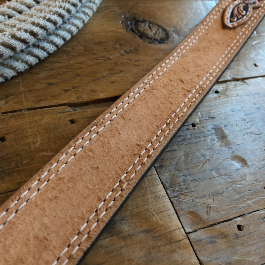 Close-up of the Hiram Belt by Savannah Sevens western life{&}style, featuring tan rough-out leather with white stitching on wood, and a coiled rope in the background.
