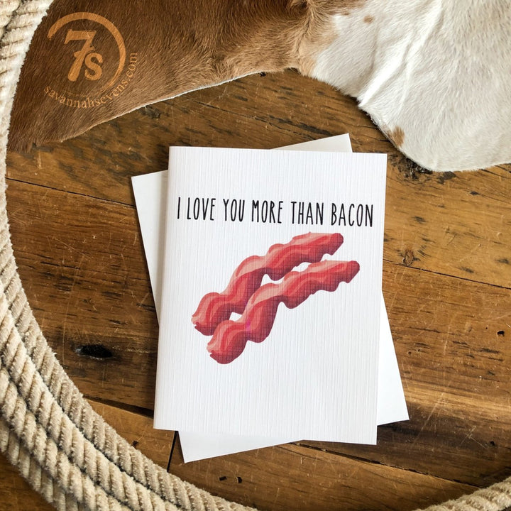 The Hungry Canyon Love You More Than Bacon Card is a blank greeting card printed on quality linen paper, featuring “I LOVE YOU MORE THAN BACON” and a drawing of bacon strips.