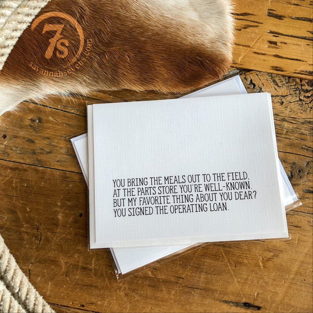 The Hungry Canyon Operating Loan Card, printed on textured linen paper, features a heartfelt farm-inspired message. A cowhide and woven rug appear in the background, capturing the unique charm of Hungry Canyon products.