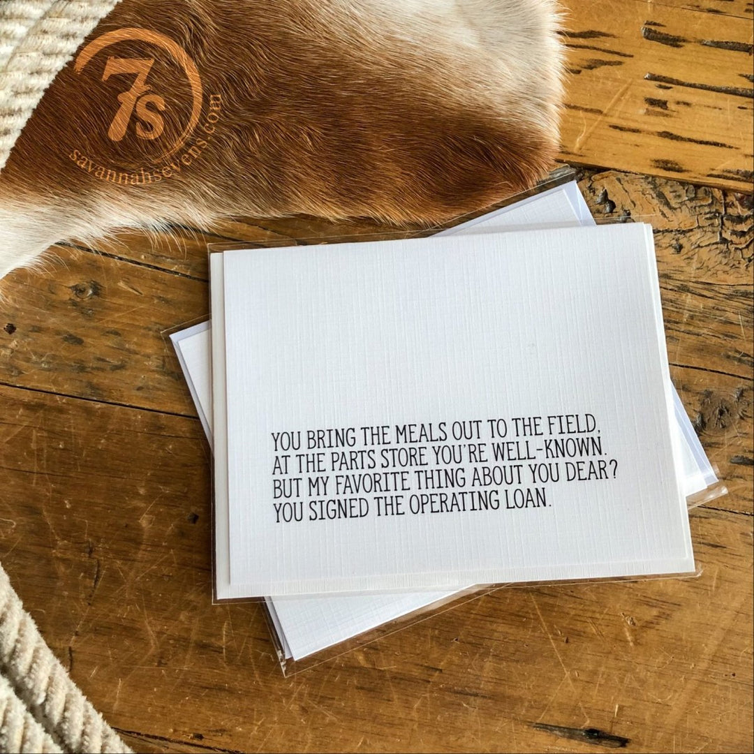 The Hungry Canyon Operating Loan Card, printed on textured linen paper, features a heartfelt farm-inspired message. A cowhide and woven rug appear in the background, capturing the unique charm of Hungry Canyon products.