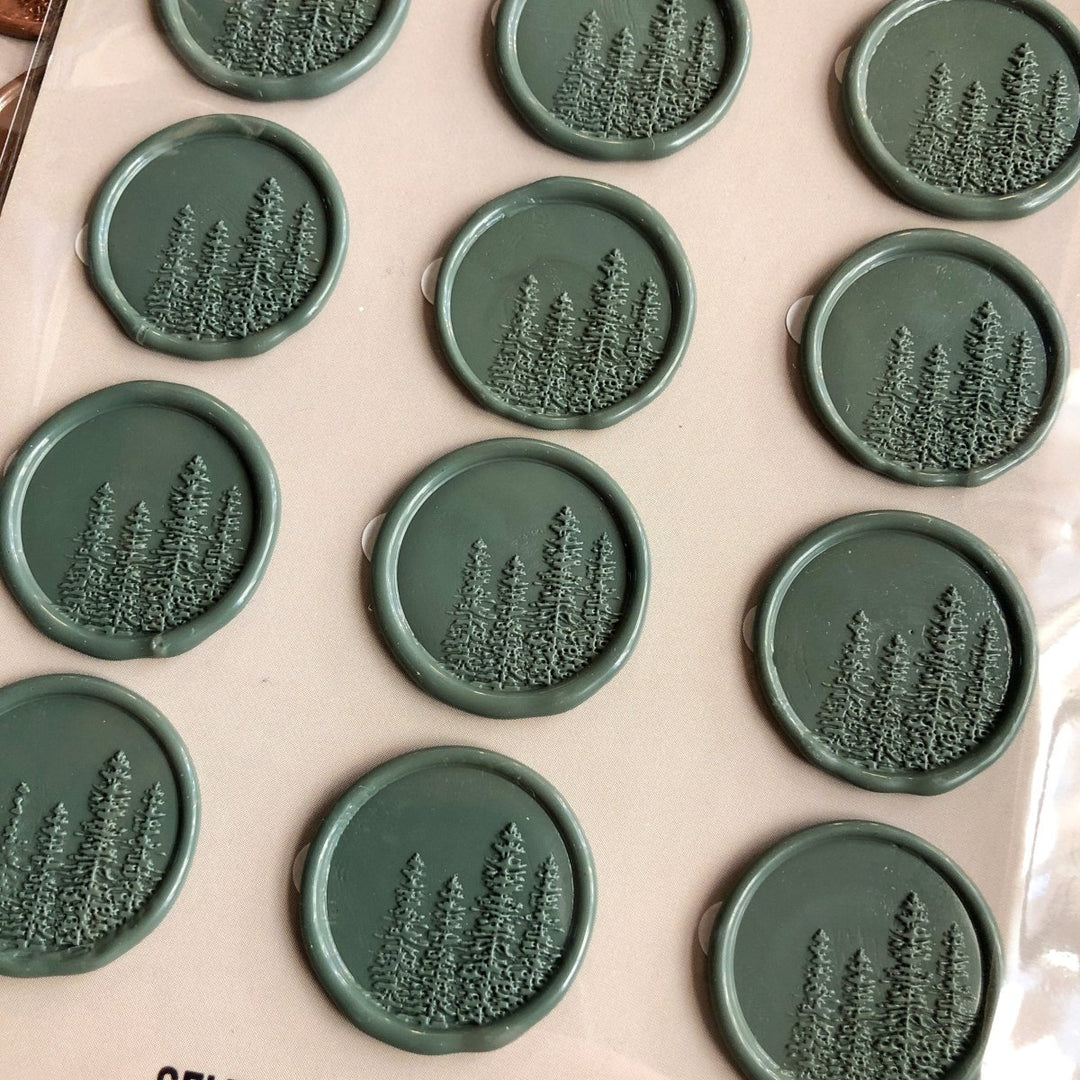 Savannah Sevens western life{&}style Pines Wax Seal features round, self-adhesive seals embossed with pine trees, neatly arranged on a light surface. Each wax stamp displays a cluster of evergreens in relief.
