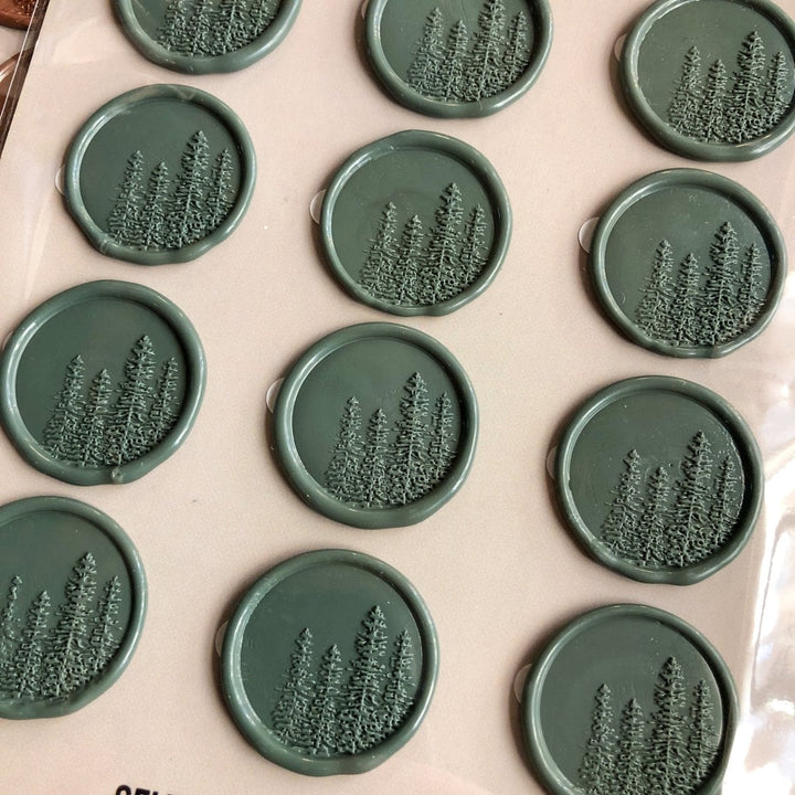Savannah Sevens western life{&}style Pines Wax Seal features round, self-adhesive seals embossed with pine trees, neatly arranged on a light surface. Each wax stamp displays a cluster of evergreens in relief.