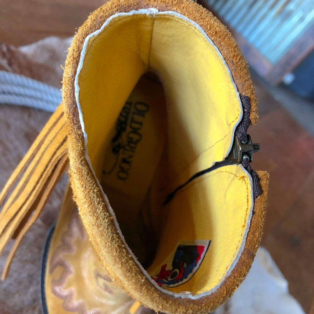 A close-up of the inside of The Tejas bootie by Savannah Sevens western life{&}style, featuring the brand label and a colorful fabric tag on the yellow and brown leather fringe inner lining.